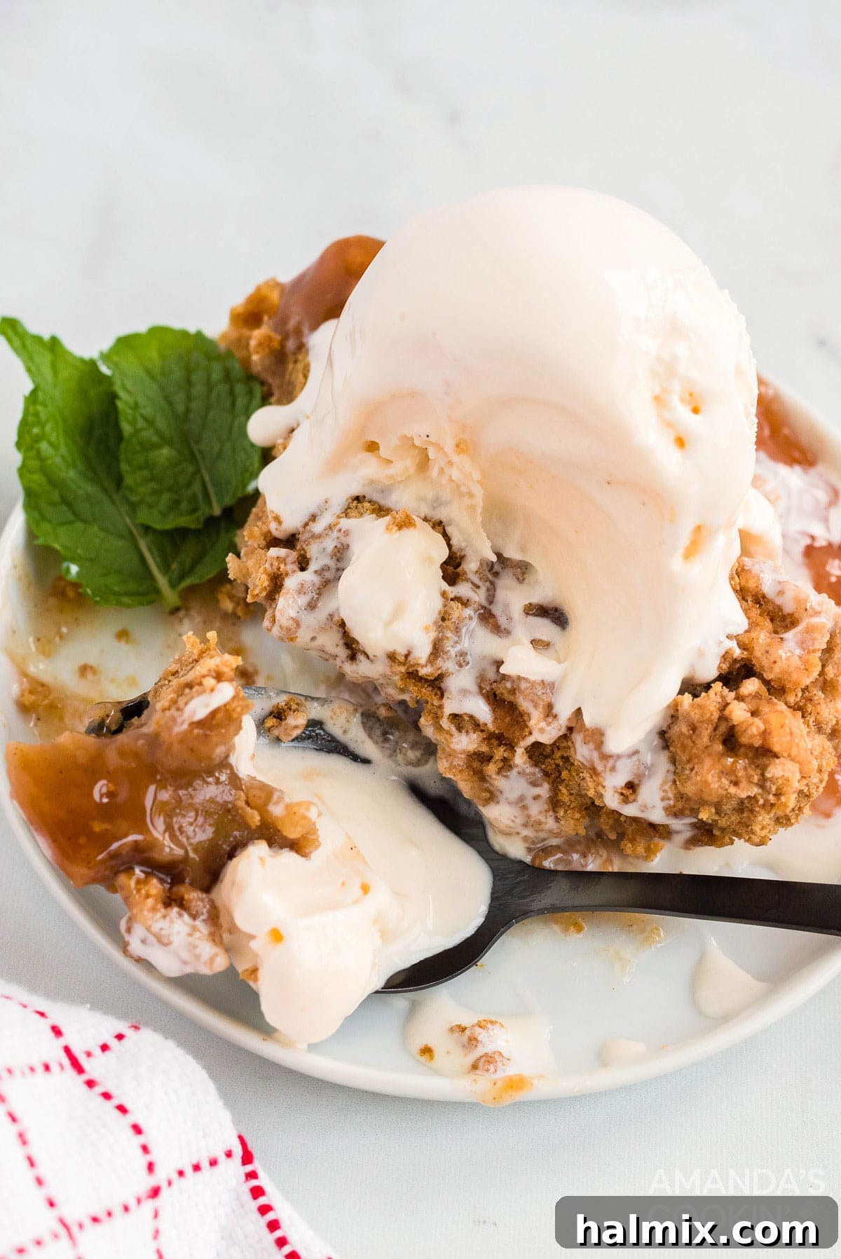 Make crockpot apple cobbler in your slow cooker. This easy crockpot dessert is quick & simple and great any time of year. apple cobbler with ice cream on a plate