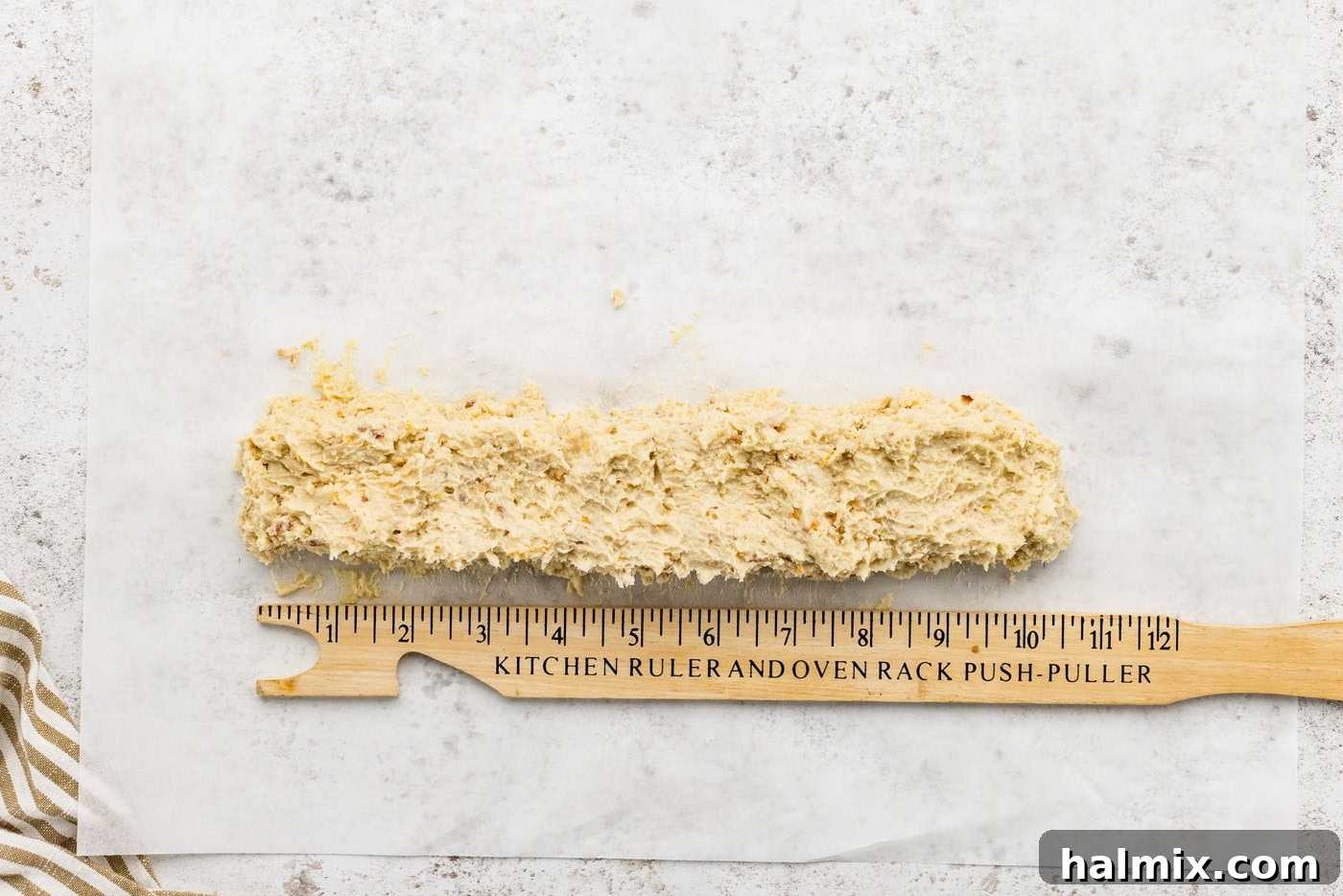 A log of icebox cookie dough with a ruler next to it, demonstrating the ideal size and shape.