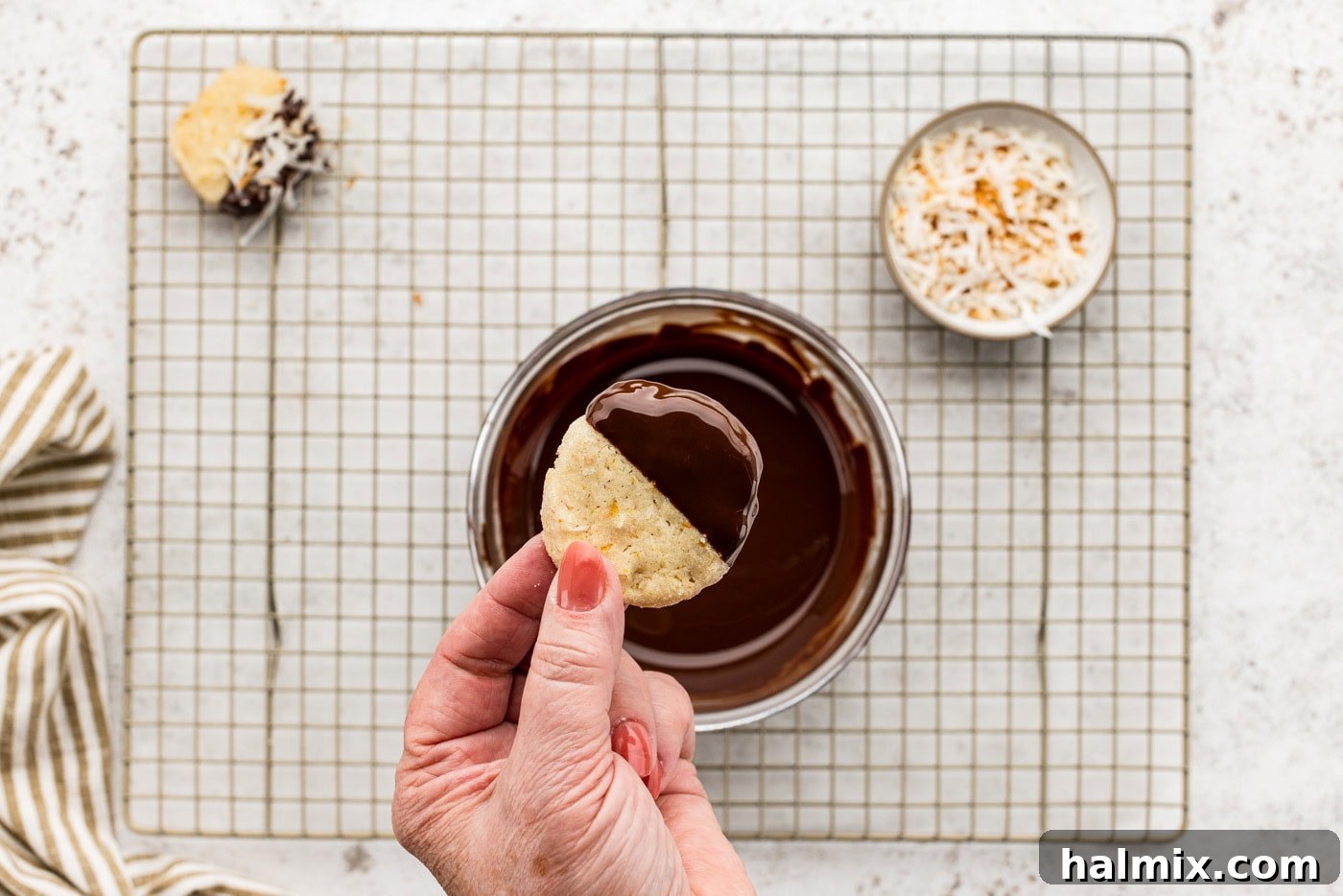 A close-up of icebox cookies, half-dipped in melted chocolate, resting on a wire cooling rack.