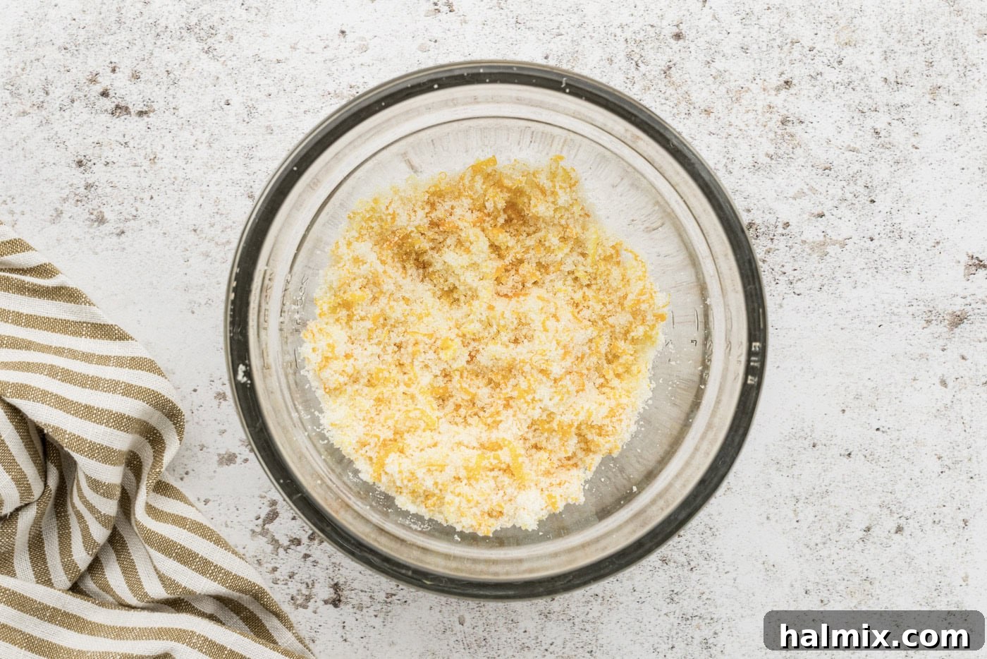 Orange zest and granulated sugar being rubbed together in a bowl, creating a fragrant mixture.