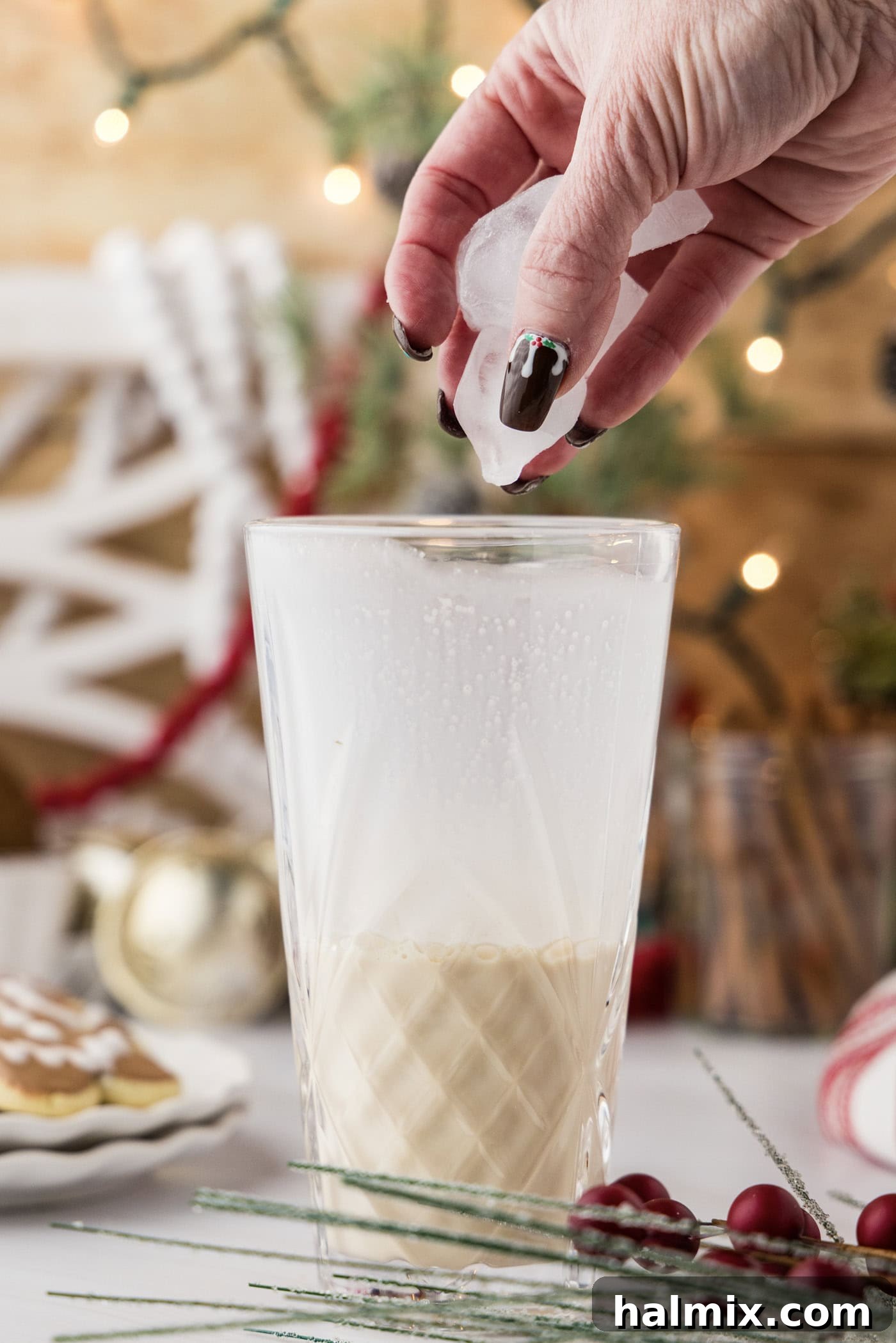 hand adding ice to a cocktail shaker with liquid