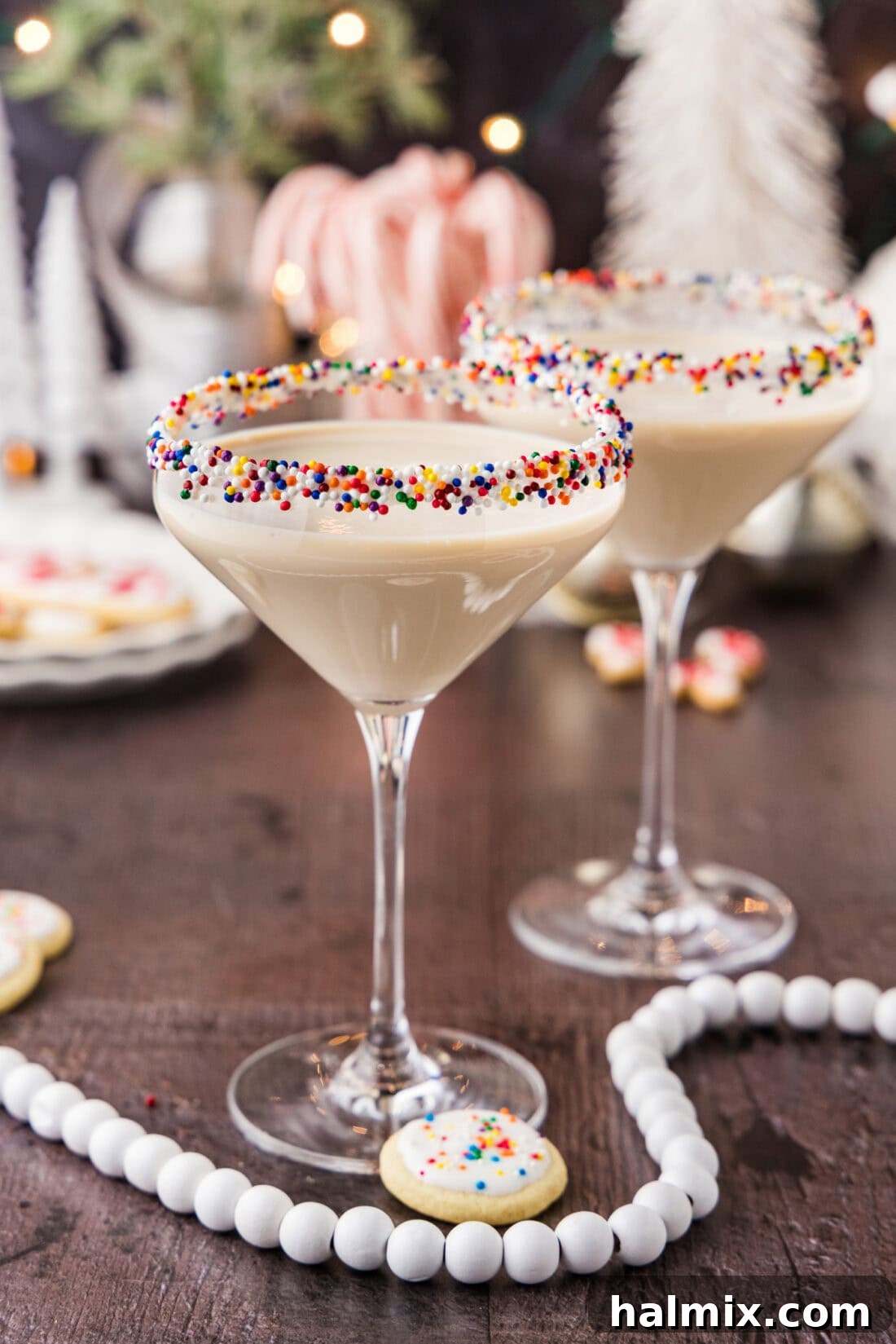 Two Sugar Cookie Martinis adorned with festive garnishes, surrounded by holiday decorations, evoking a warm and celebratory atmosphere.