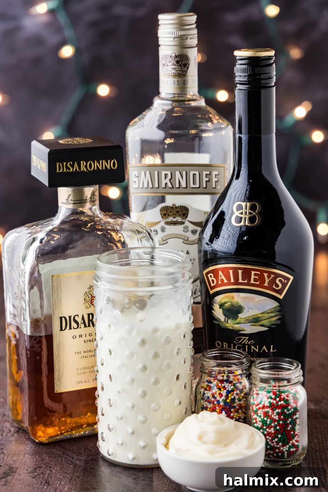 A curated display of ingredients necessary for preparing the Sugar Cookie Martini, including bottles of Irish cream, vanilla vodka, amaretto, and a carton of milk.