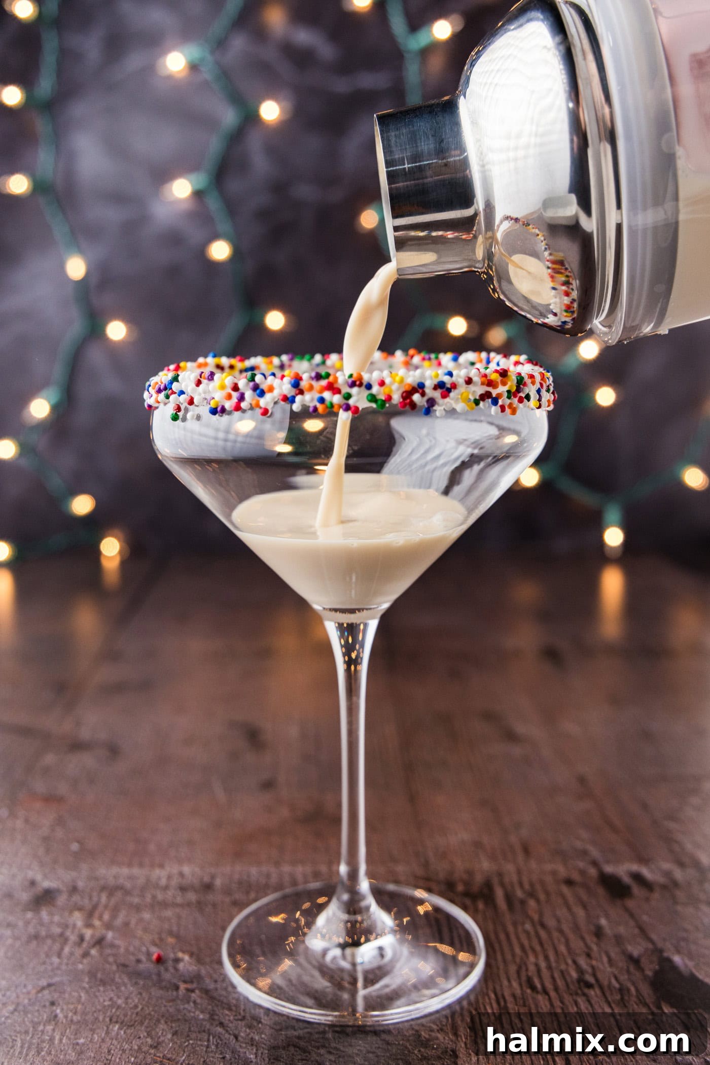 A Sugar Cookie Martini being strained from a cocktail shaker into a chilled martini glass, ready for final garnishing.