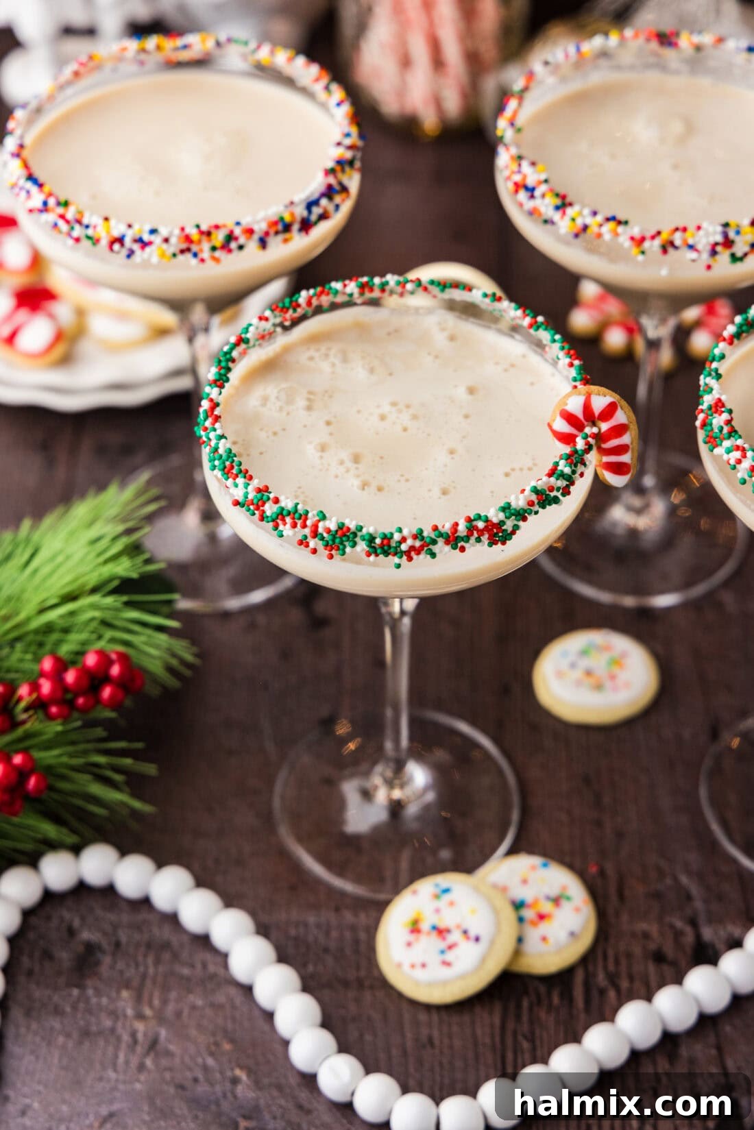 An overhead shot showcasing three perfectly crafted Sugar Cookie Martinis, each with a frosted rim and mini cookie garnish, presented beautifully on a reflective surface.