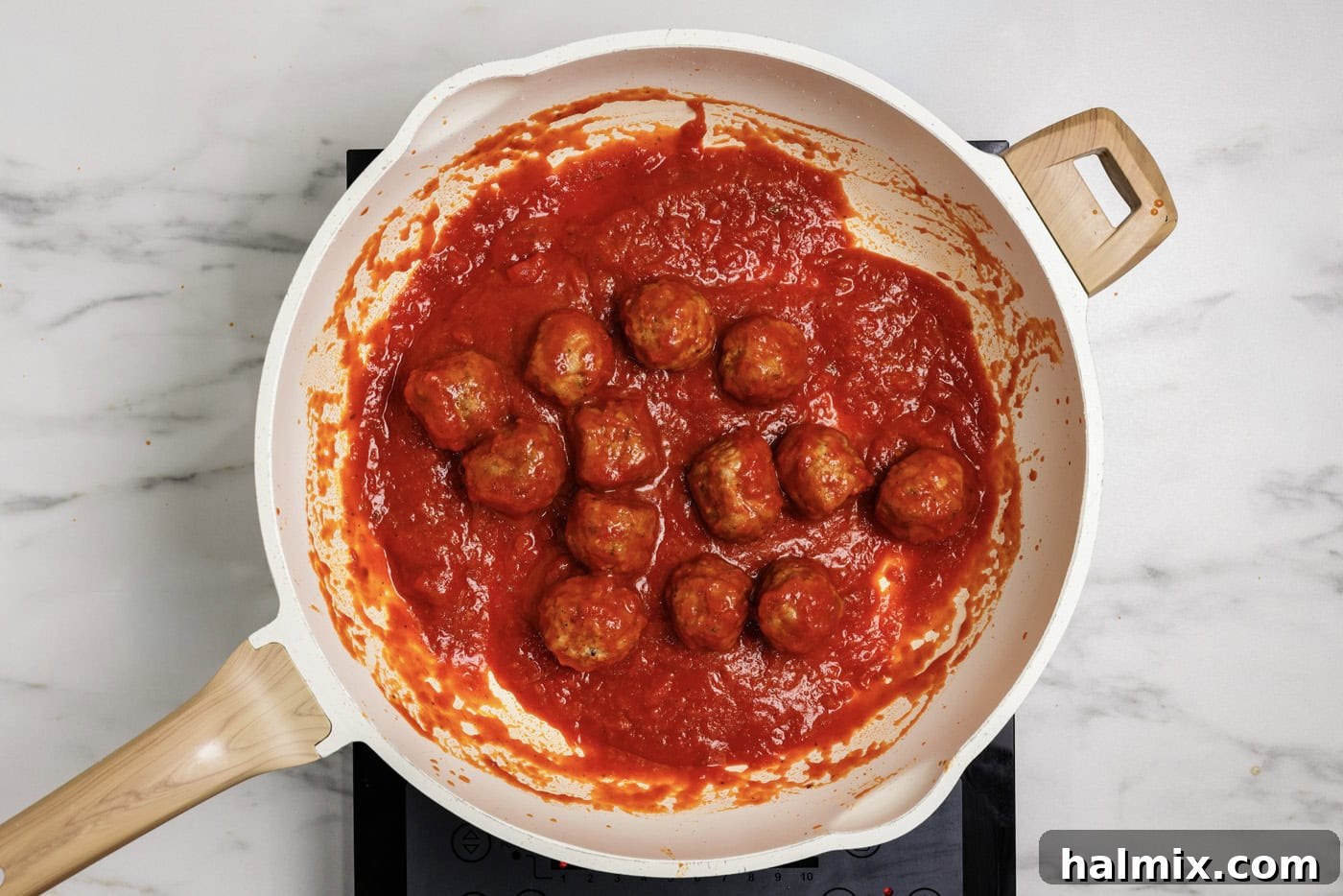 Pocket-Sized Meatball Delights 5 Frozen meatballs simmering in a skillet with rich marinara sauce, preparing for assembly.