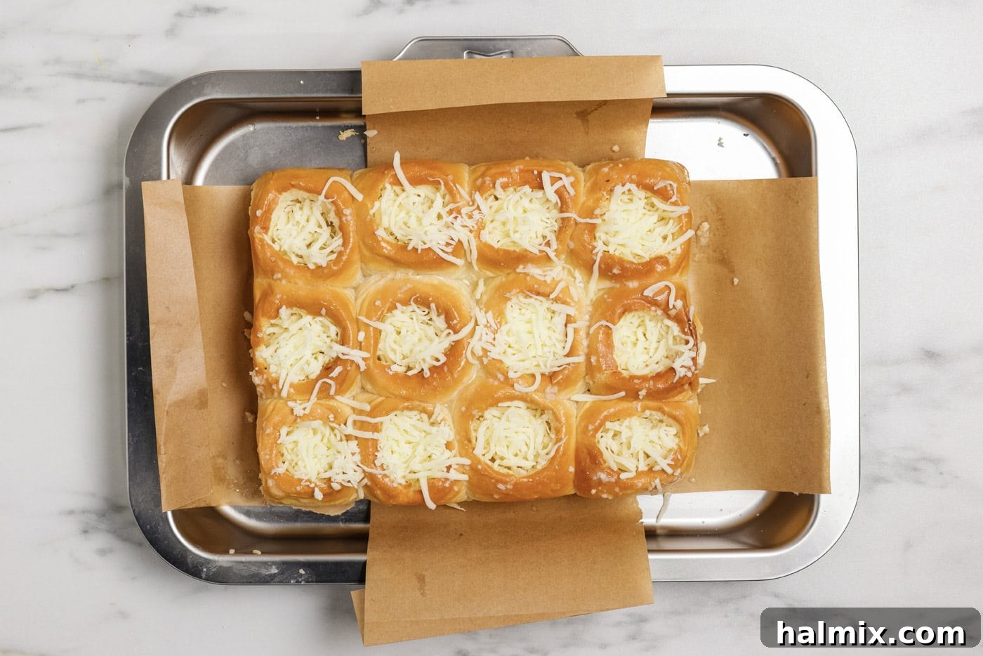 Pocket-Sized Meatball Delights 7 Shredded mozzarella cheese filling the pre-cut holes in the dinner rolls, ready for the next layer of ingredients.