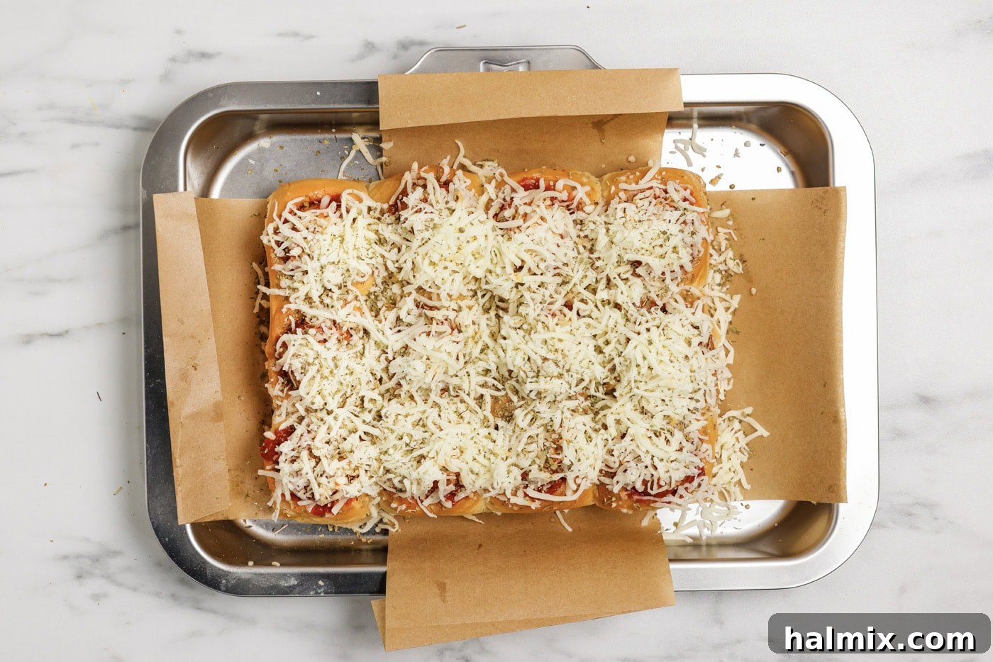 Pocket-Sized Meatball Delights 9 Generous amount of shredded mozzarella cheese and a sprinkle of Italian seasoning covering the meatball sliders before baking.