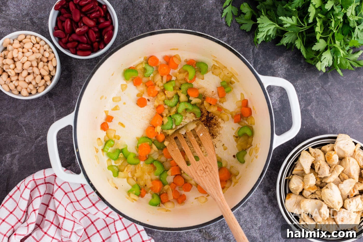 A mix of sautéed celery, onion, carrots, and pureed tomatoes simmering in a Dutch oven, forming the soup base.