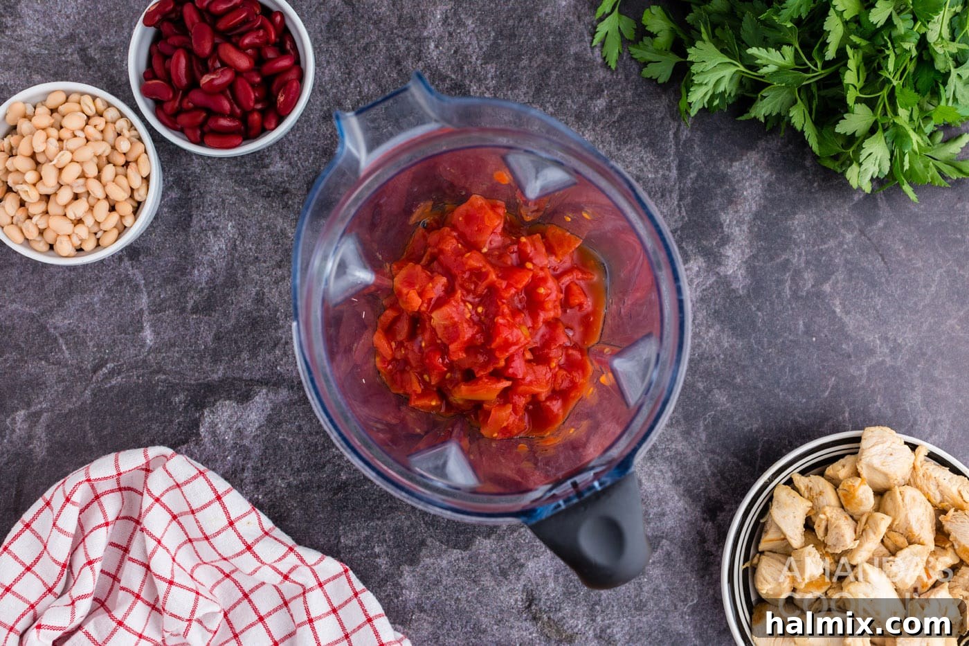 Canned tomatoes being pureed in a food processor to create a smooth, rich tomato base for the soup.
