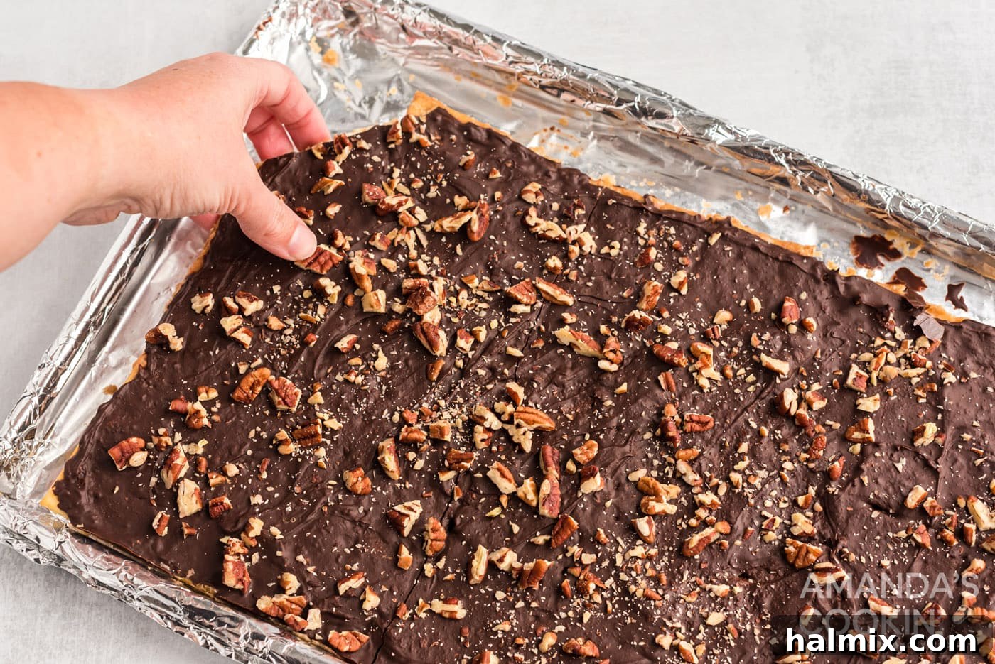 Hand breaking off a piece of finished saltine toffee