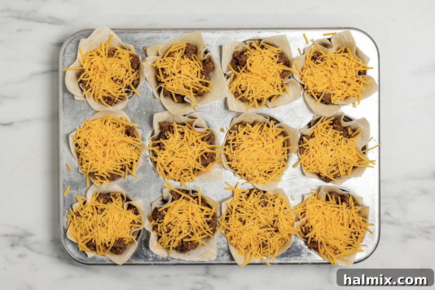 Mini Taco Bites 9 final layer of shredded cheese on top of taco cups in a muffin pan