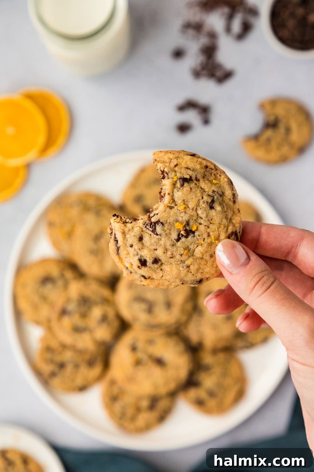 Hand holding a Orange Chocolate Chip Cookie above a plate of cookies