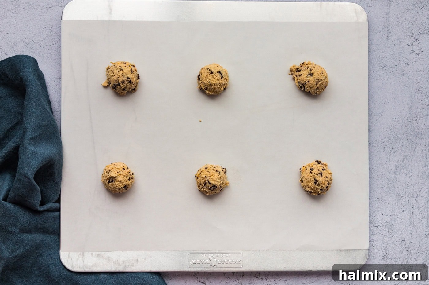 orange chocolate chip cookie dough balls on a parchment lined baking sheet