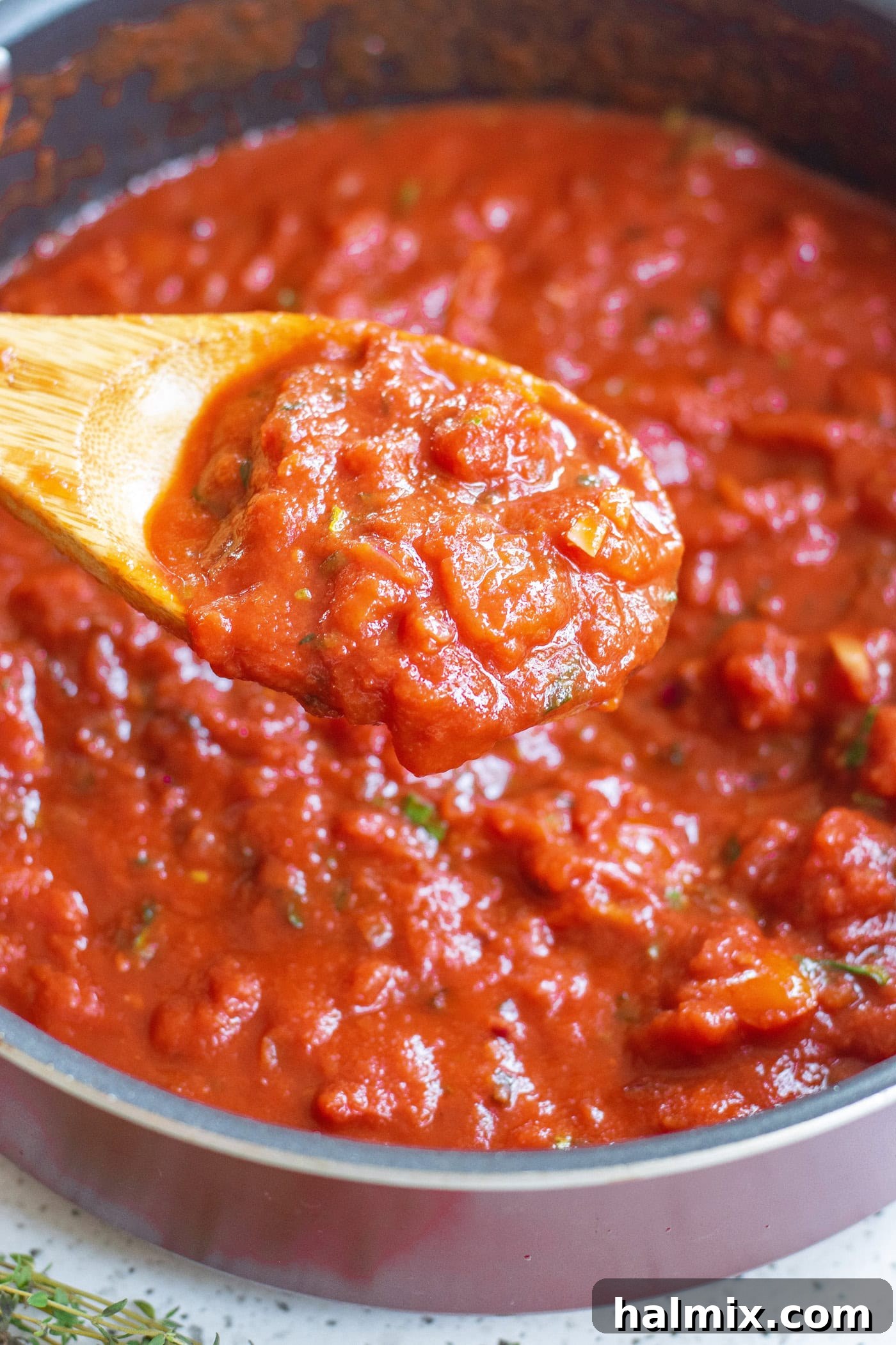 A wooden spoon gently stirring a pot of simmering marinara sauce, showcasing its vibrant color and consistency.