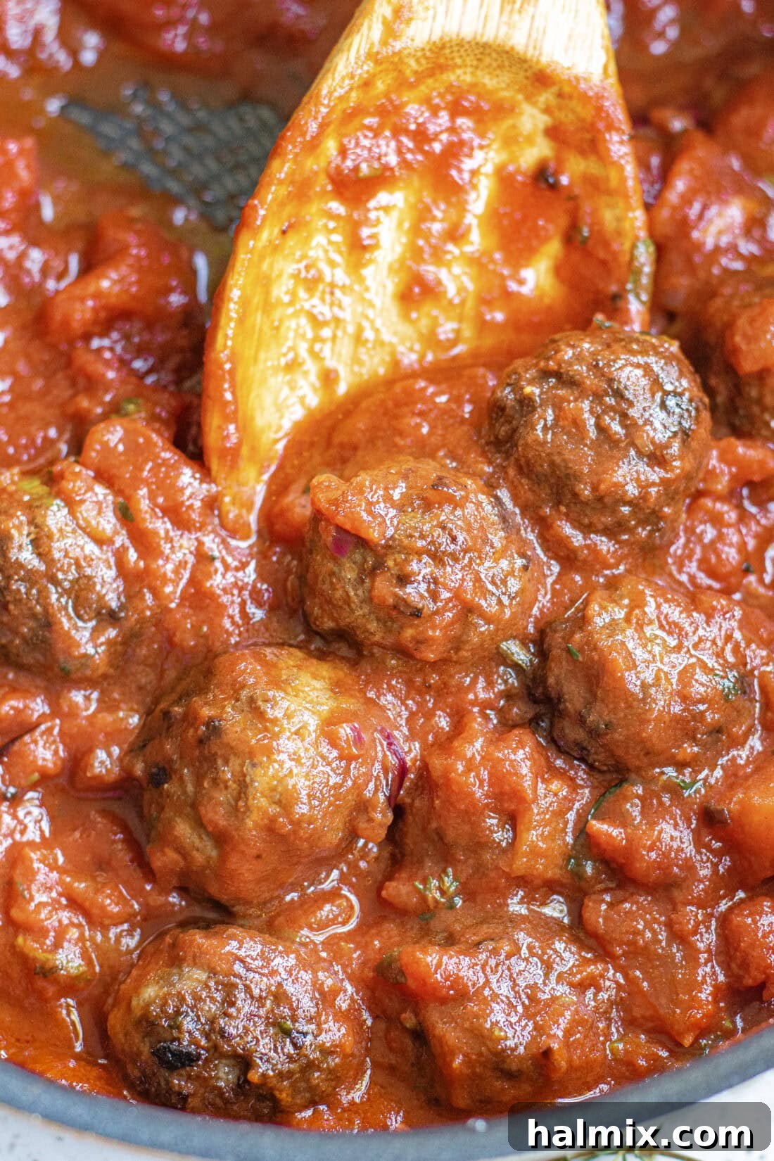 Classic Marinara Sauce 8 A spoon stirring a skillet of delectable meatballs generously coated in homemade marinara sauce, perfect for a hearty meal.