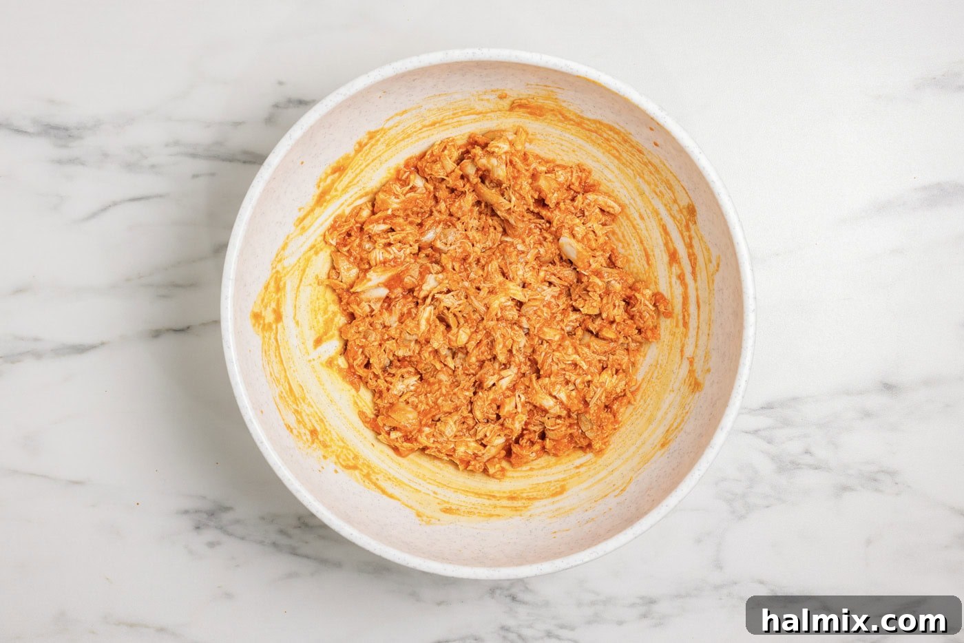 Zesty Buffalo Chicken Bell Pepper Bake 7 Shredded chicken in a bowl mixed with buffalo sauce