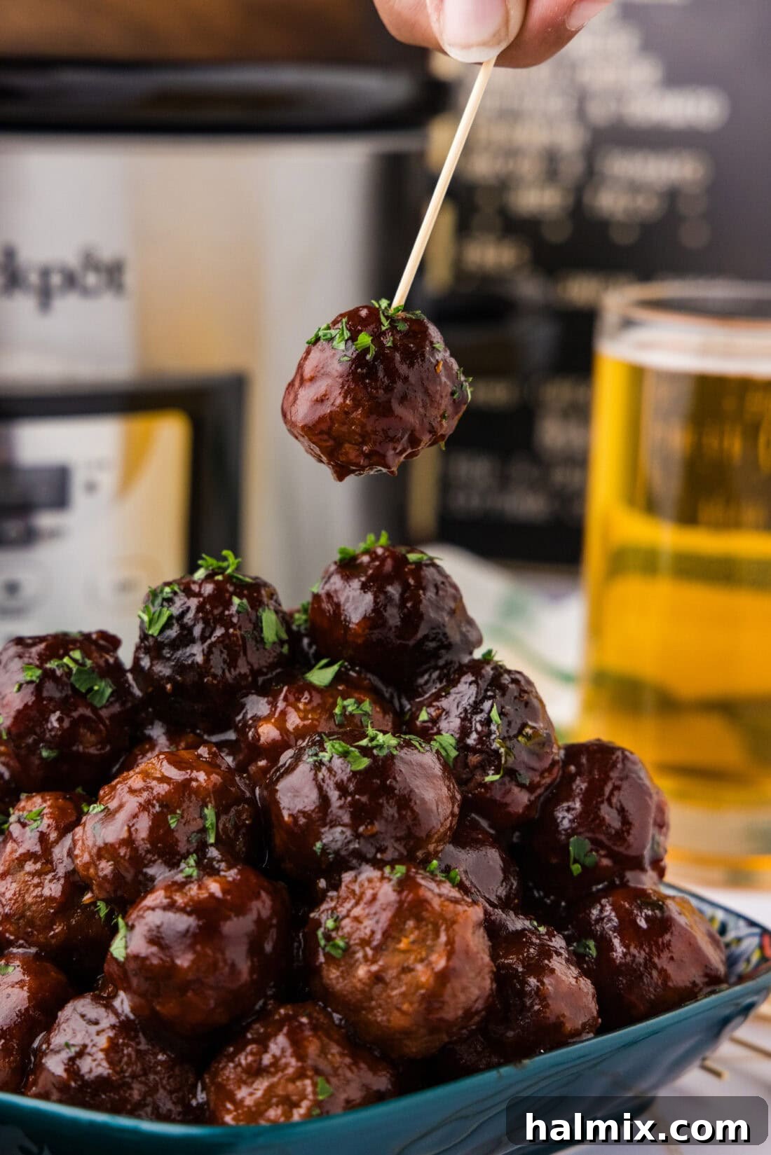 BBQ Meatball on a toothpick held above a pile of BBQ Meatballs
