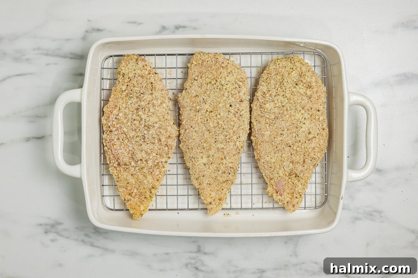 Crispy Parmesan Chicken 7 parmesan and breadcrumb coated chicken breast in a baking pan lined with a wire rack