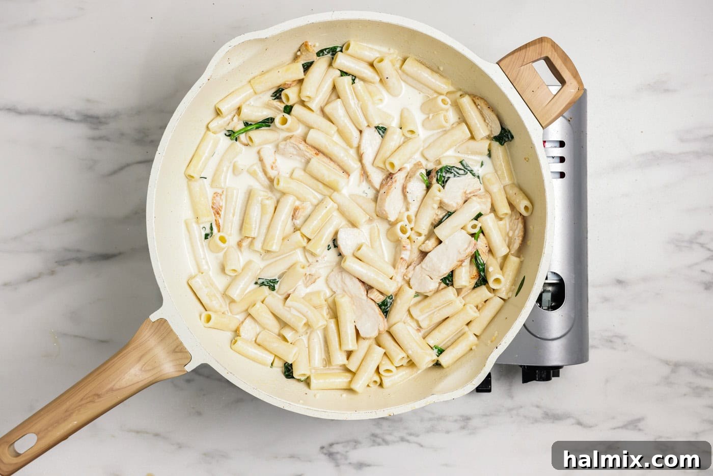 A large skillet filled with creamy garlic chicken pasta, garnished and ready to be served.
