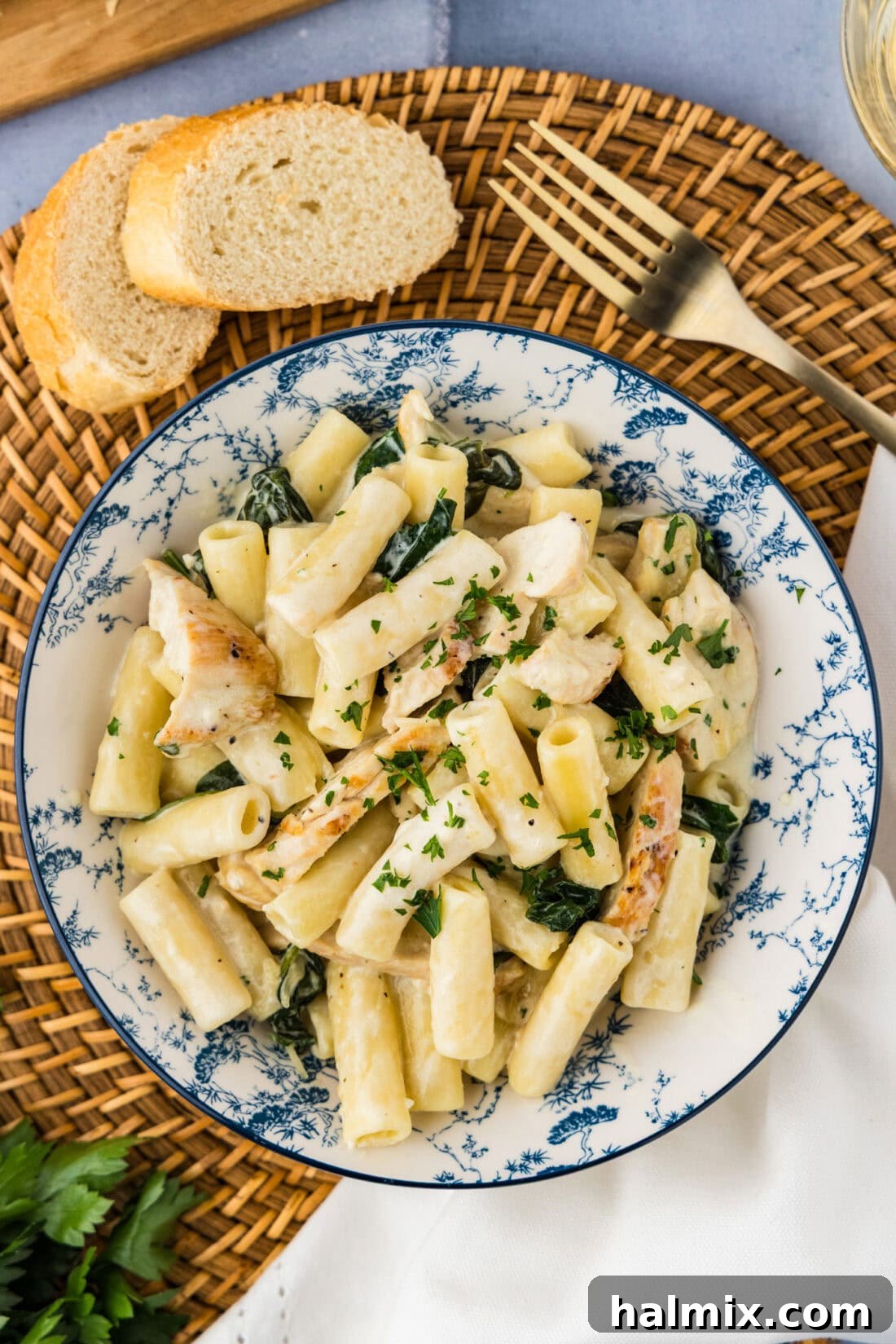 Overhead photo of a serving of Creamy Garlic Chicken Pasta in a white bowl, garnished with fresh herbs.