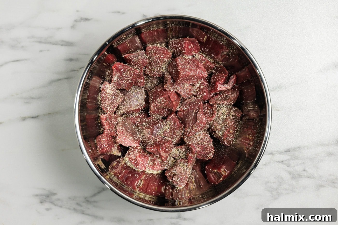 Cubed sirloin beef in a bowl with seasonings