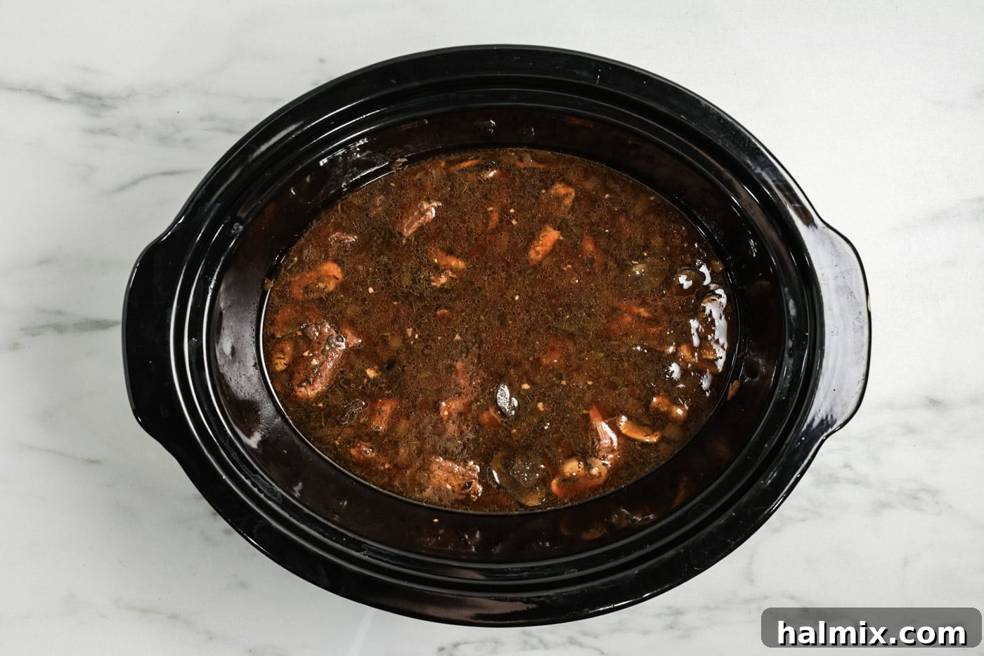 Beef broth added to crock pot with cubed beef, mushrooms, onions, and seasonings