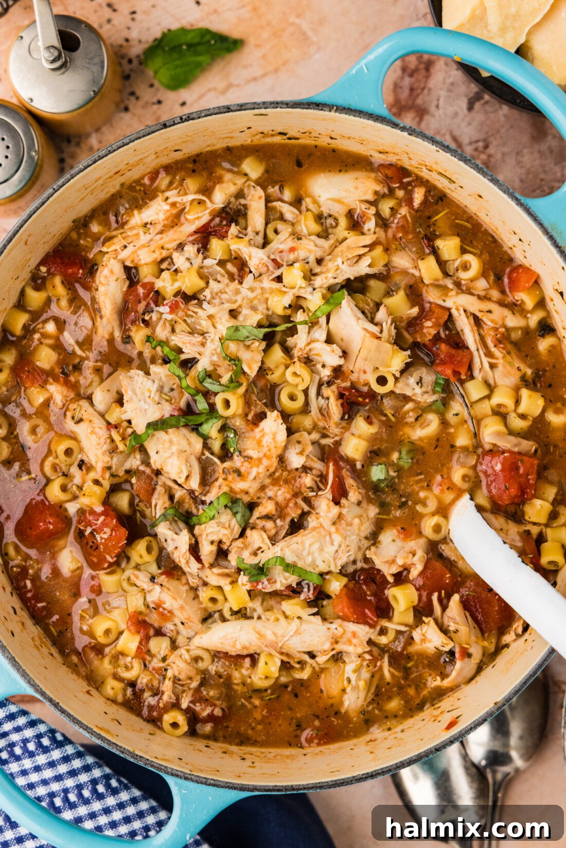 Close up photo of a spoon dipping into a pot of rich Chicken Parmesan Soup, showing the texture and ingredients.