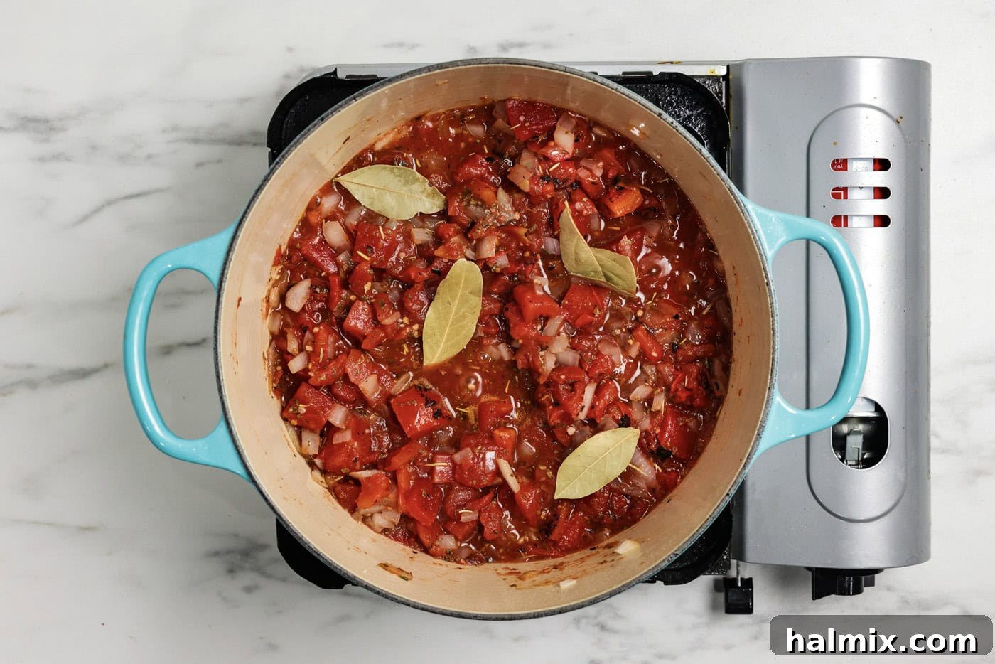 Basil added to pot with tomatoes and seasonings for a rich Italian base.