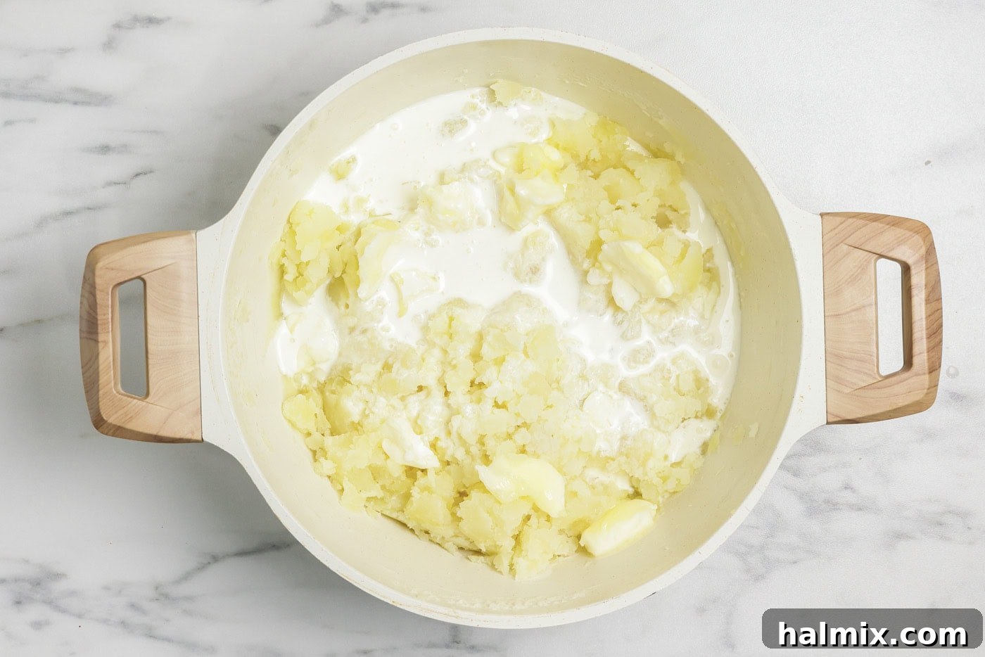 Colcannon: Ireland's Signature Mash 7 Heavy cream and butter being added to a stockpot filled with freshly mashed potatoes.