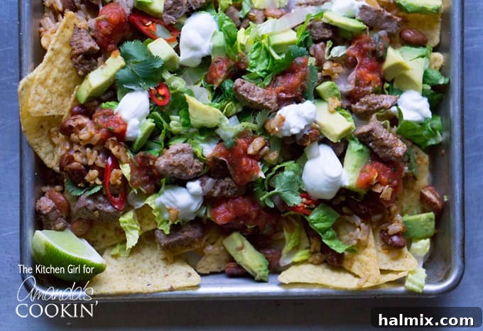 A close-up overhead photo of Filet Mignon Steak Nachos, highlighting the textures of the steak, cheese, and fresh toppings.