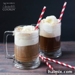 A photo of two root beer float cocktails in clear mugs served with a red and white striped straw.