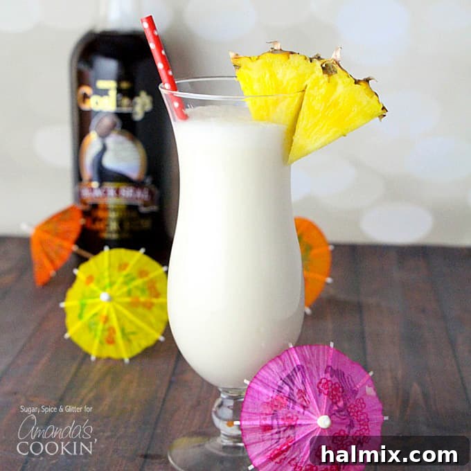 Pina Colada served in a tall glass with pineapple and cherry garnish.