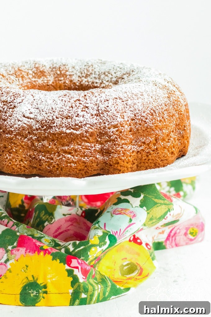 Vibrant green pistachio bundt cake on an elegant cake stand, ready to be served, dusted with powdered sugar.