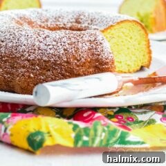 A beautifully presented pistachio bundt cake with a slice removed, garnished lightly with powdered sugar, ready for serving.