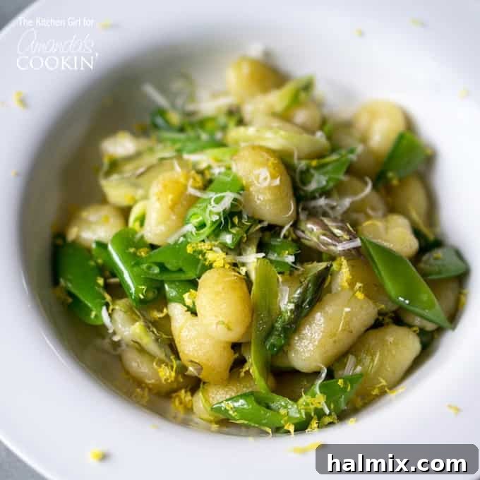 Crispy Gnocchi with Asparagus Ribbons and Snap Peas 2 A close up overhead photo of pan seared gnocchi with shaved asparagus and snap peas in a white bowl.