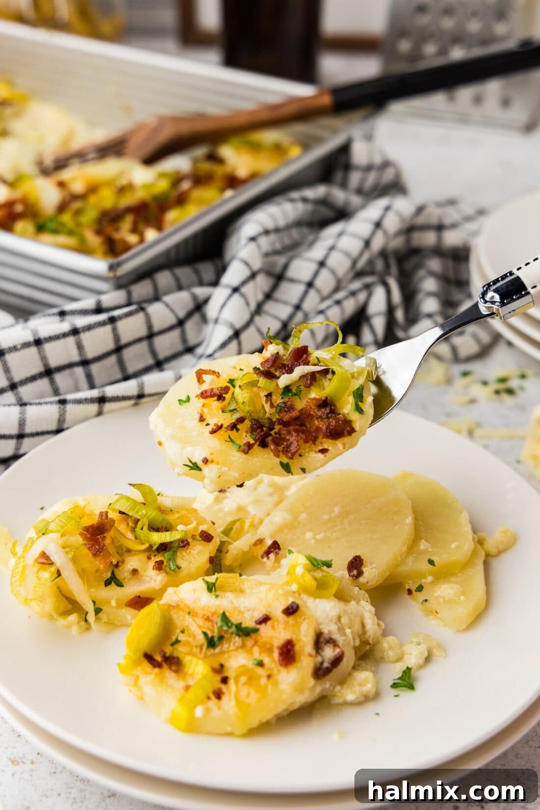 A close up of a forkful of potatoes au gratin with bacon and leeks.