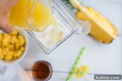 Adding pineapple juice to a blender with other Pina Colada ingredients.
