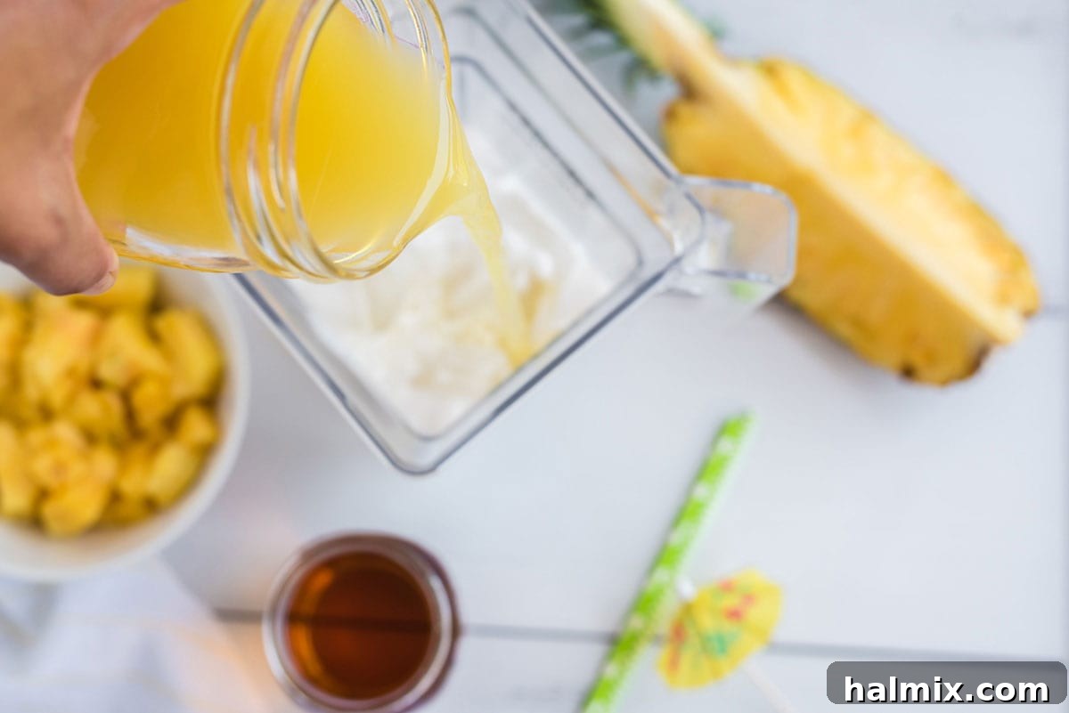 Pouring fresh pineapple juice into a blender along with other Pina Colada ingredients.