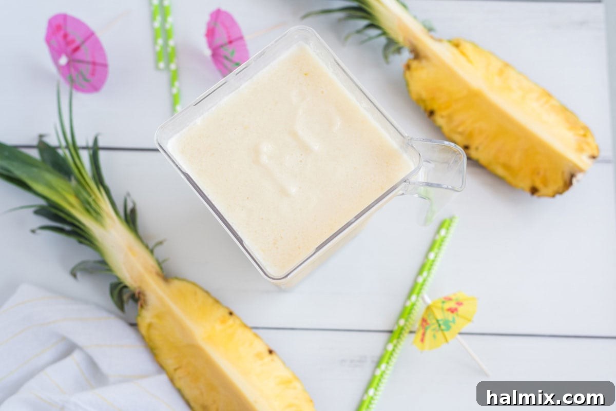 A blender filled with a creamy, frosty Pina Colada mixture, ready to be poured.
