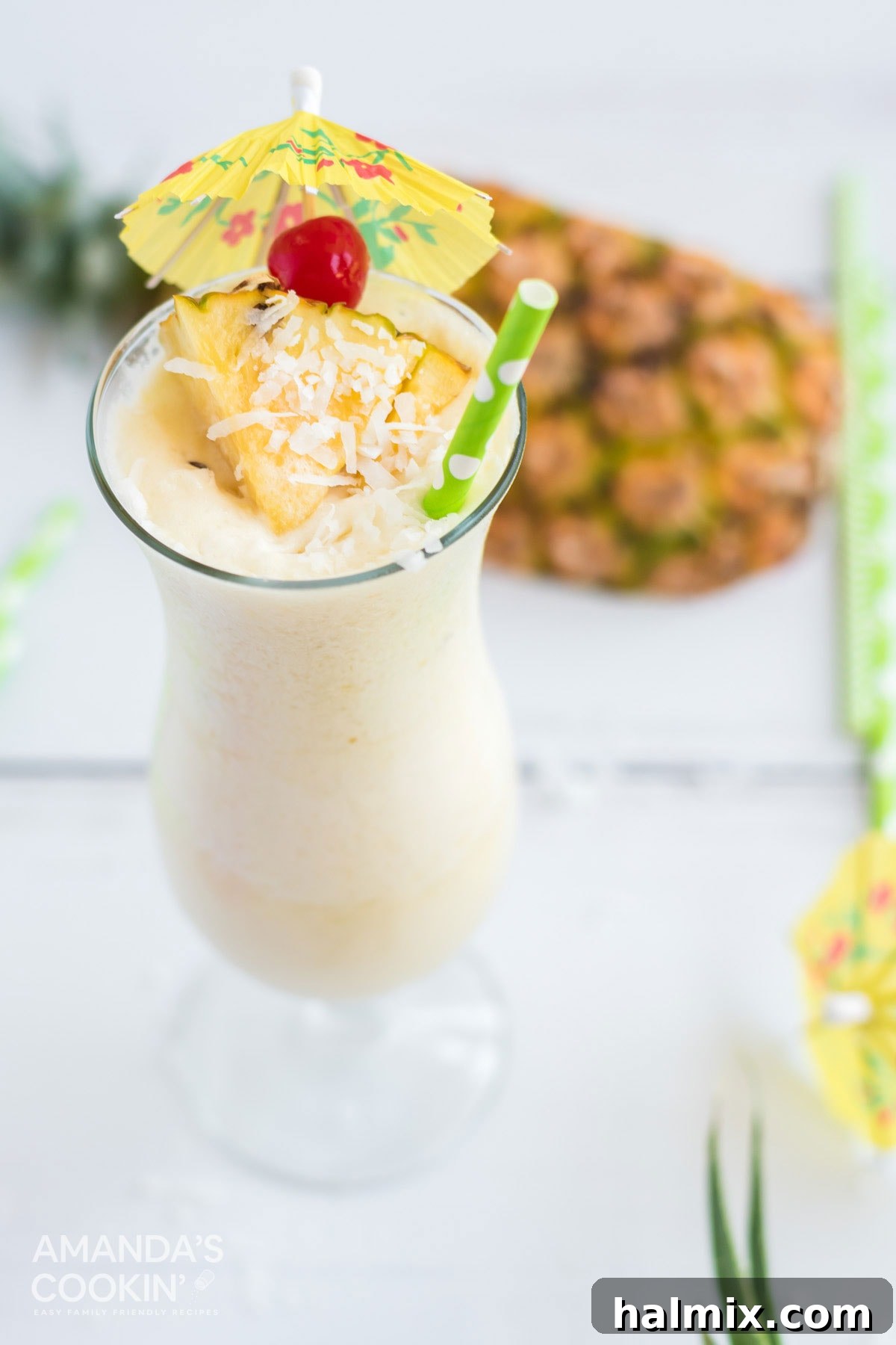 A pristine white Pina Colada, beautifully garnished with a red cherry and a fresh pineapple wedge, presented in a hurricane glass.