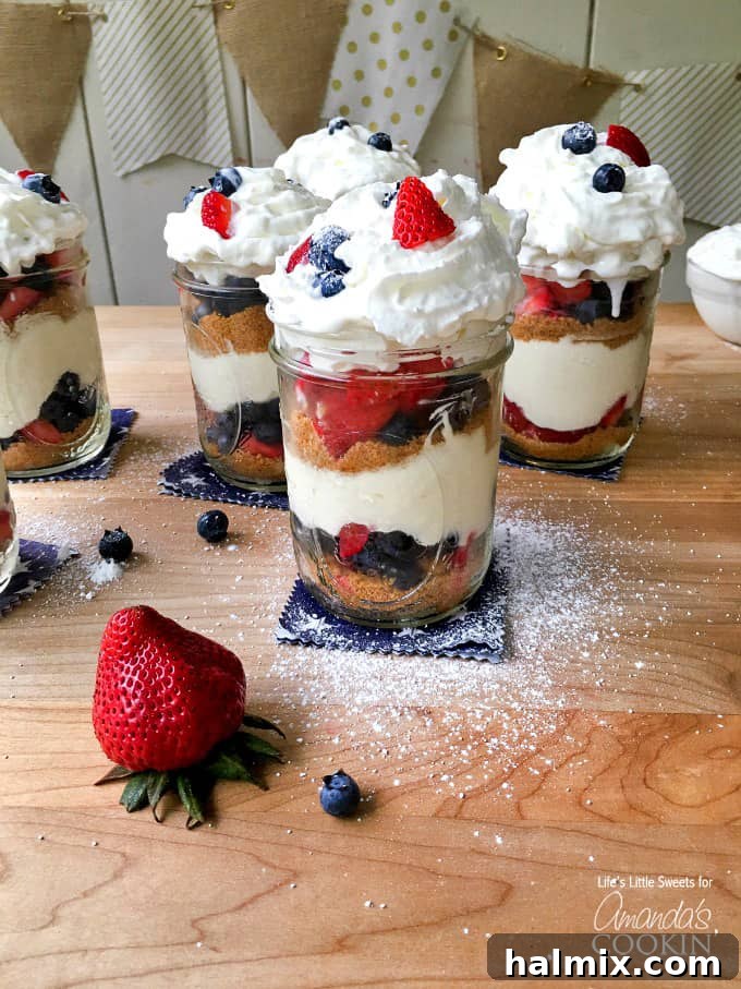 No-Bake Berry Cheesecake Trifle Jars 3 A close up of no bake berry cheesecake trifles in mason jars on a wooden cutting board.
