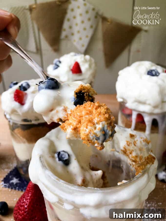 No-Bake Berry Cheesecake Trifle Jars 5 A close up of spoonful of no bake berry cheesecake trifles with more in the background.