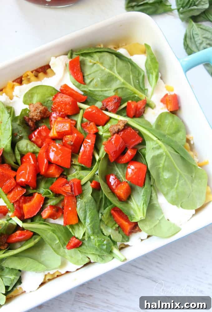 Layered Pizza Bake 13 A photo of ricotta cheese on lasagna noodles, covered with fresh spinach and vibrant chopped red peppers.