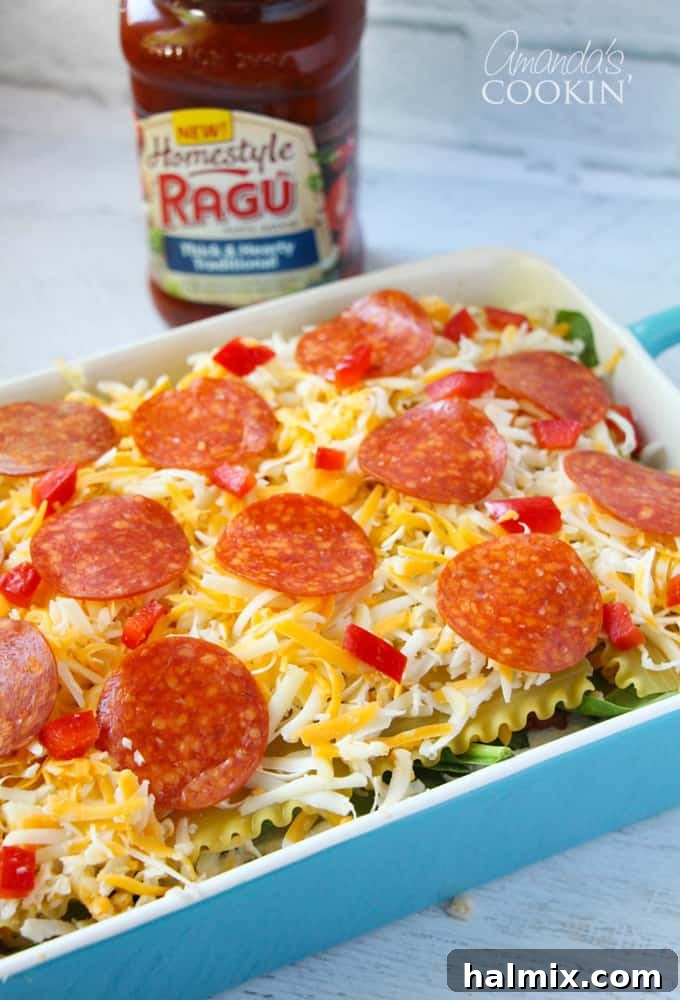Layered Pizza Bake 15 A close up photo of the unbaked pizza lasagna, generously topped with cheese, pepperoni, and red peppers.