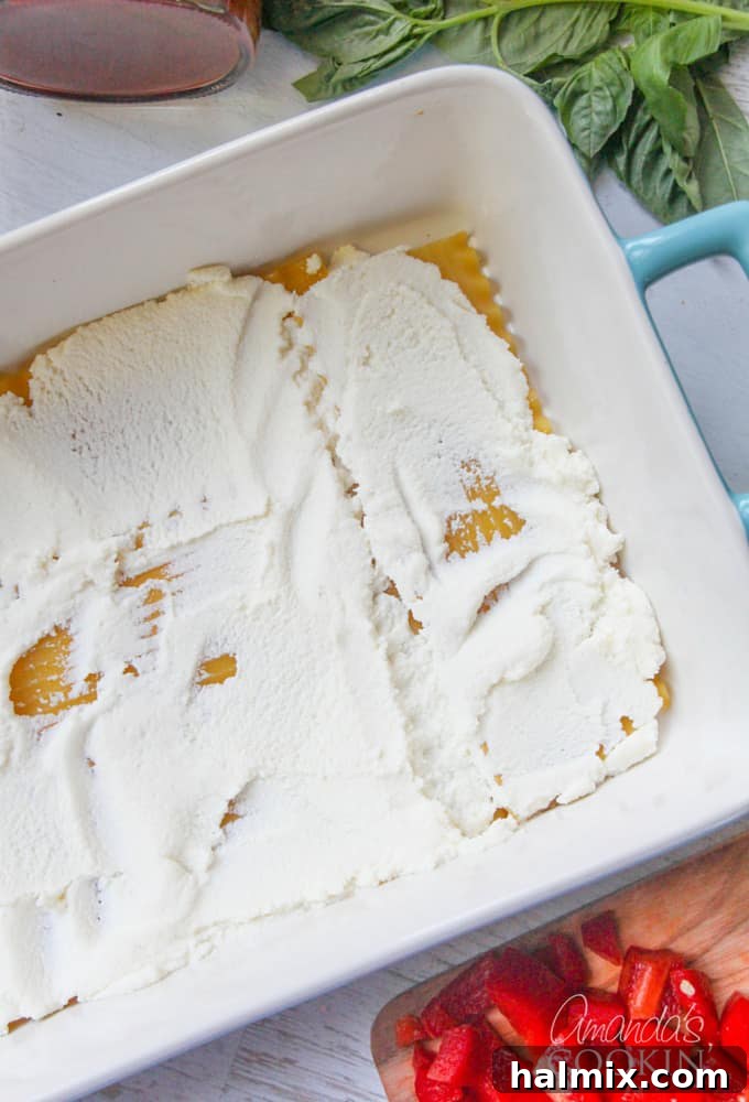 Layered Pizza Bake 8 An overhead photo of lasagna noodles in a baking pan with a creamy layer of ricotta cheese spread on top.