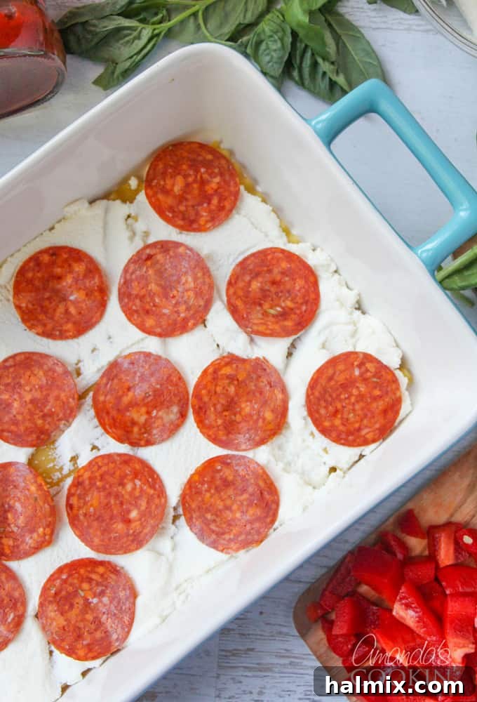 Layered Pizza Bake 9 An overhead photo of lasagna noodles with ricotta cheese and generously placed pepperoni slices.