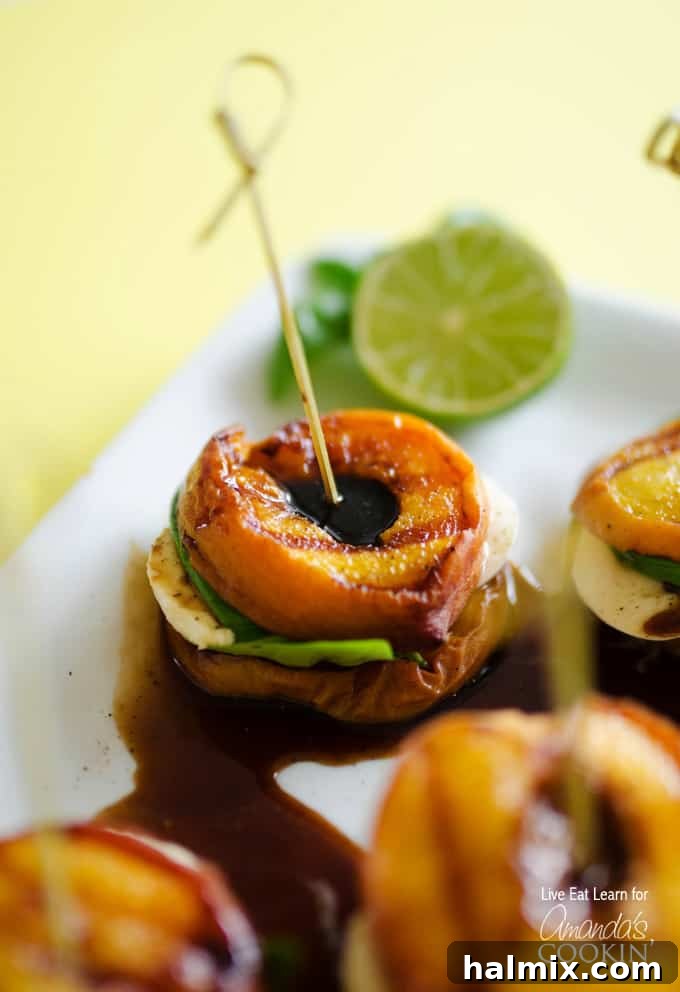 A close up of grilled peach caprese on a white platter with a lime wheel in the background, highlighting the freshness of the ingredients.