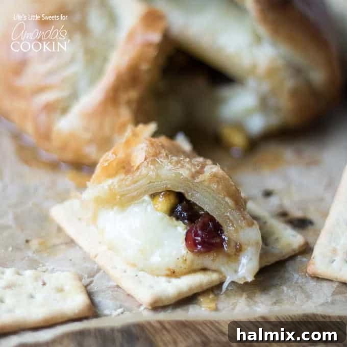 baked brie on a cutting board, garnished with fruit and nuts, ready to serve as an elegant appetizer.