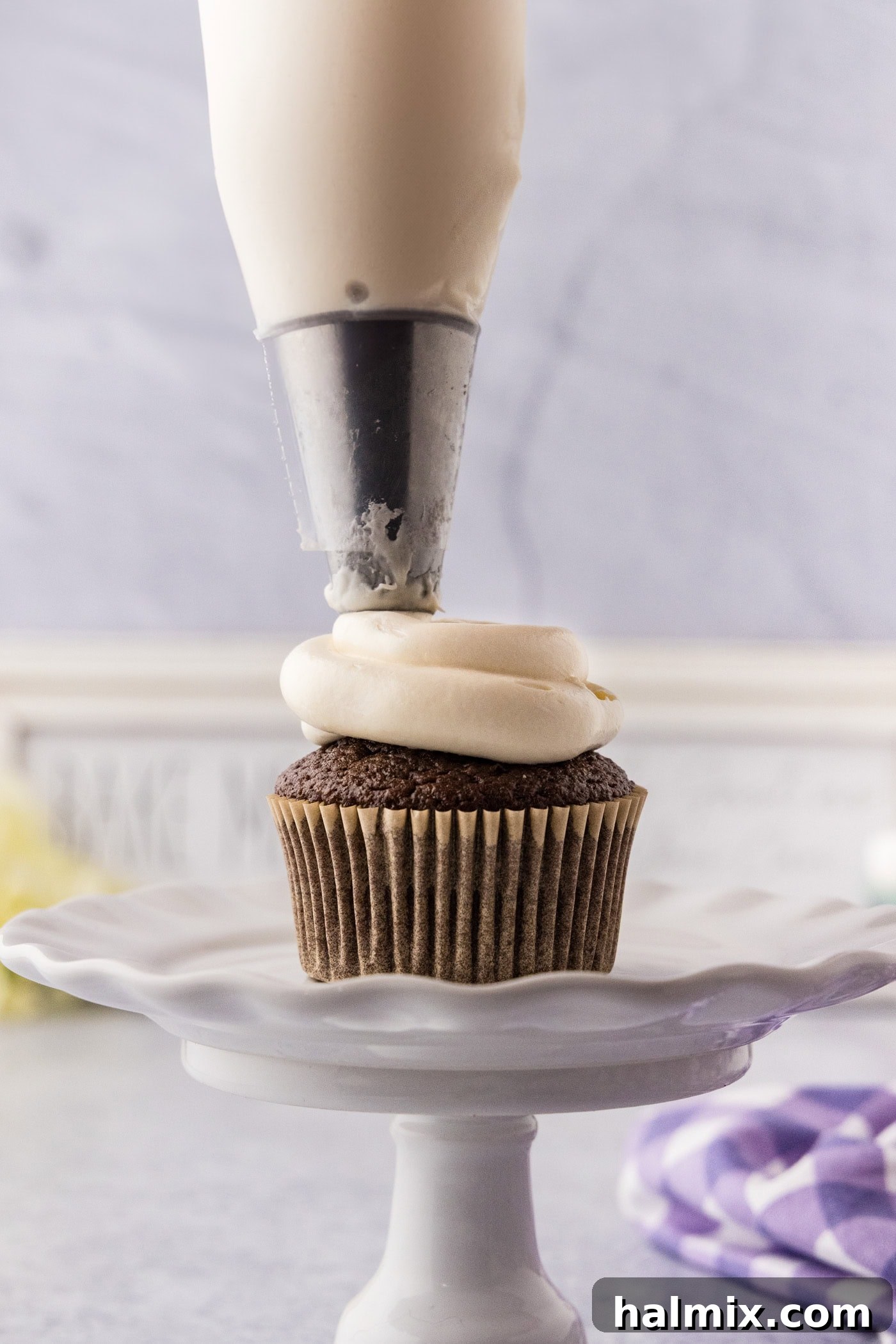 Marshmallow Frosting being expertly piped onto a chocolate cupcake